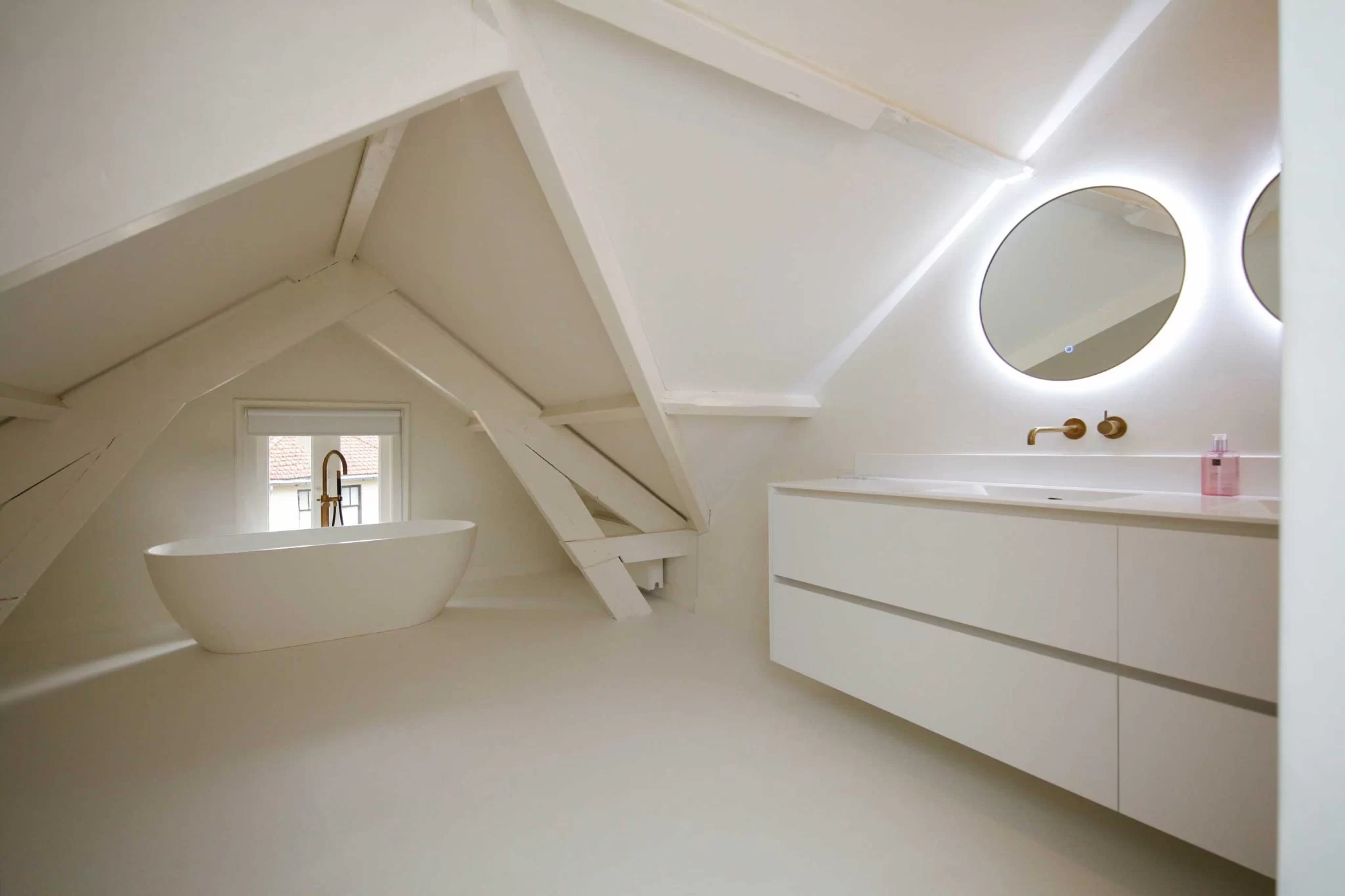 Badkamer onder de dakbalken met ronde spiegel